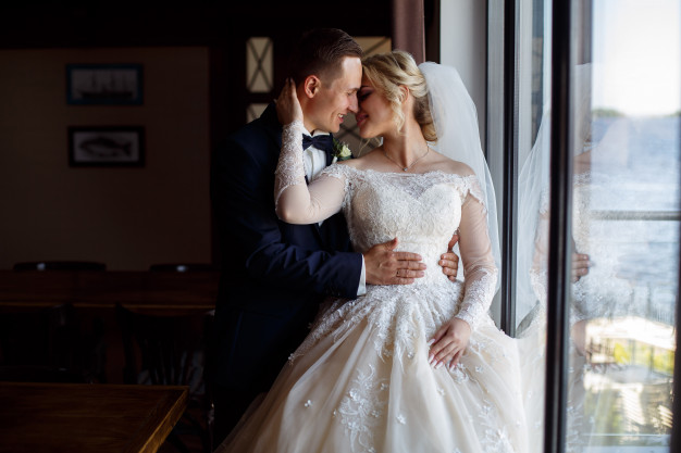 bride-groom-kisses-tenderly-emotional-photo-couple-love-wedding-day-smiling-newlyweds-near-big-window-wedding-photography_133138-313